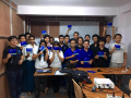 Group Photo at the end of Fedora 23 Release + Translation Workshop in Myanmar; Everyone is holding Fedora 23 Workstation Live DVD (64bits) in hand.